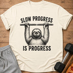 Cream t-shirt with sloth graphic and "SLOW PROGRESS IS PROGRESS" text.