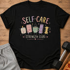 Black t-shirt with "SELF-CARE STRENGTH CLUB" text and cute characters.