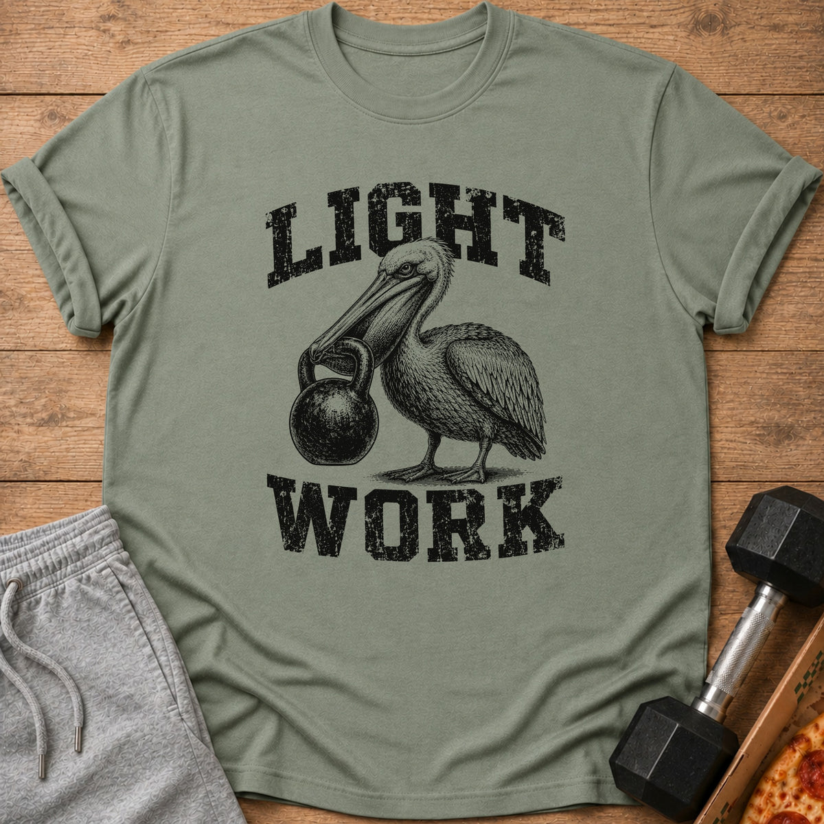 Olive green t-shirt with black distressed text "LIGHT WORK" and a pelican holding a kettlebell.
