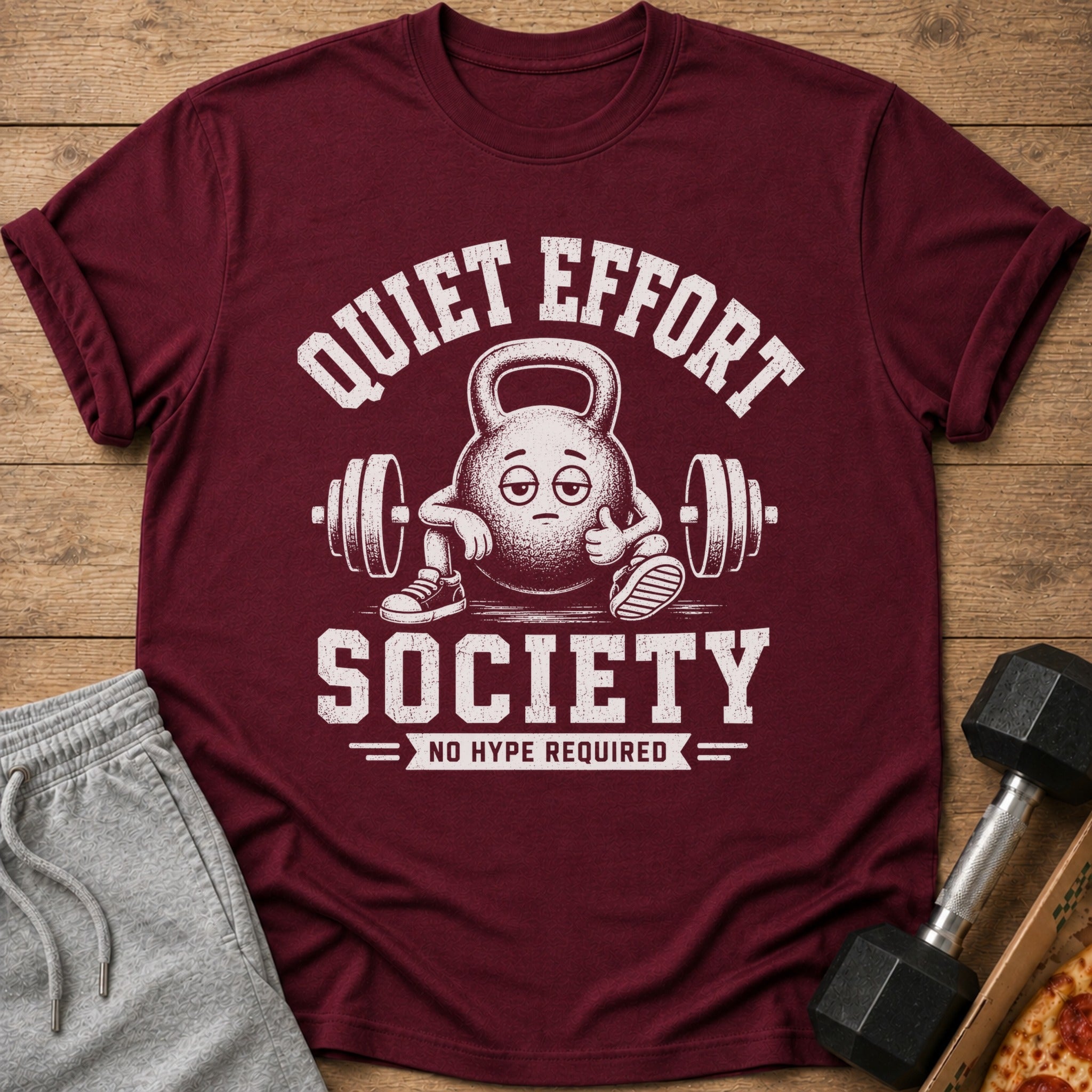 Maroon t-shirt with cartoon kettlebell graphic and text "QUIET EFFORT SOCIETY NO HYPE REQUIRED".