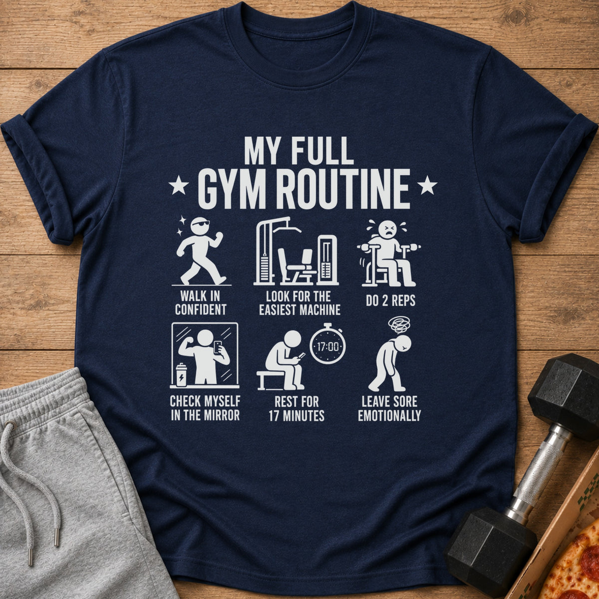 Navy t-shirt with humorous gym routine text and icons: walk in confident, easiest machine, 2 reps, mirror selfie, rest, leave sore.