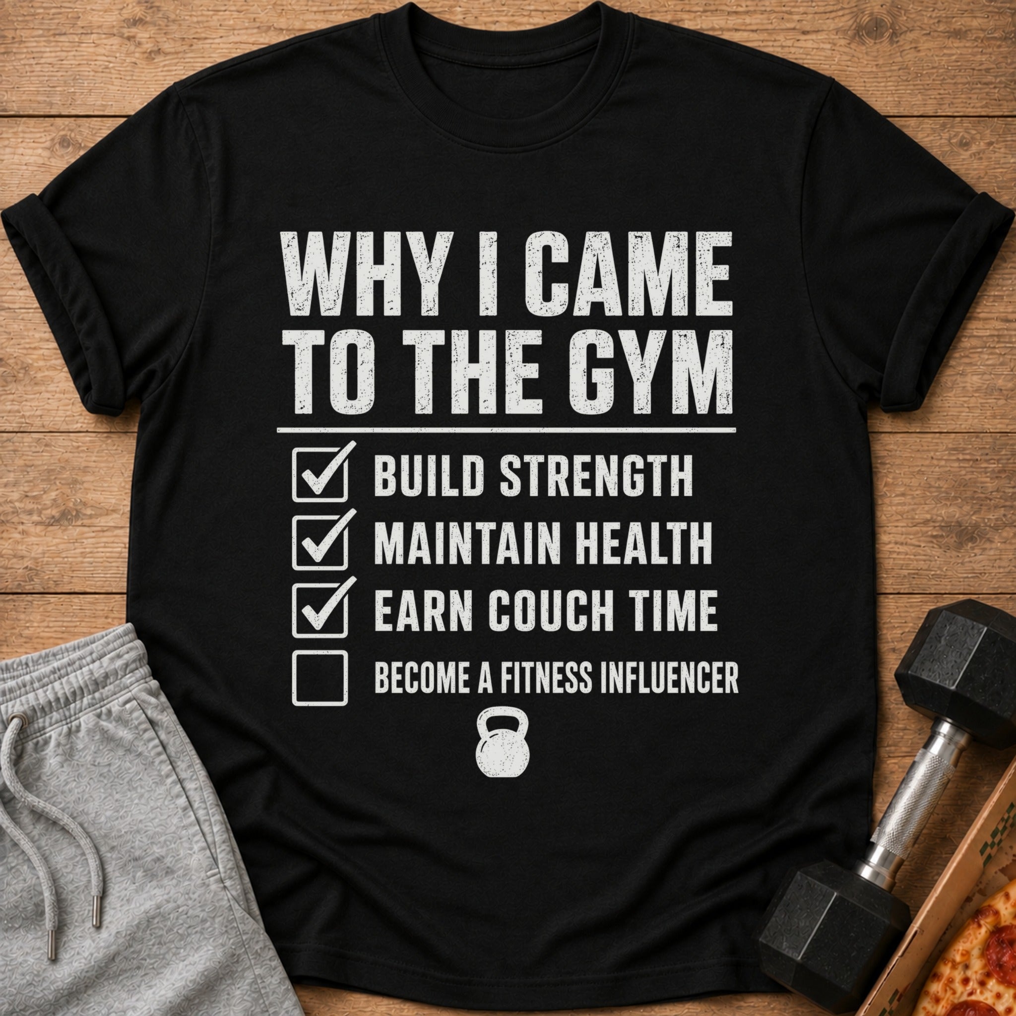 Black t-shirt listing gym goals: build strength, maintain health, earn couch time, become fitness influencer.