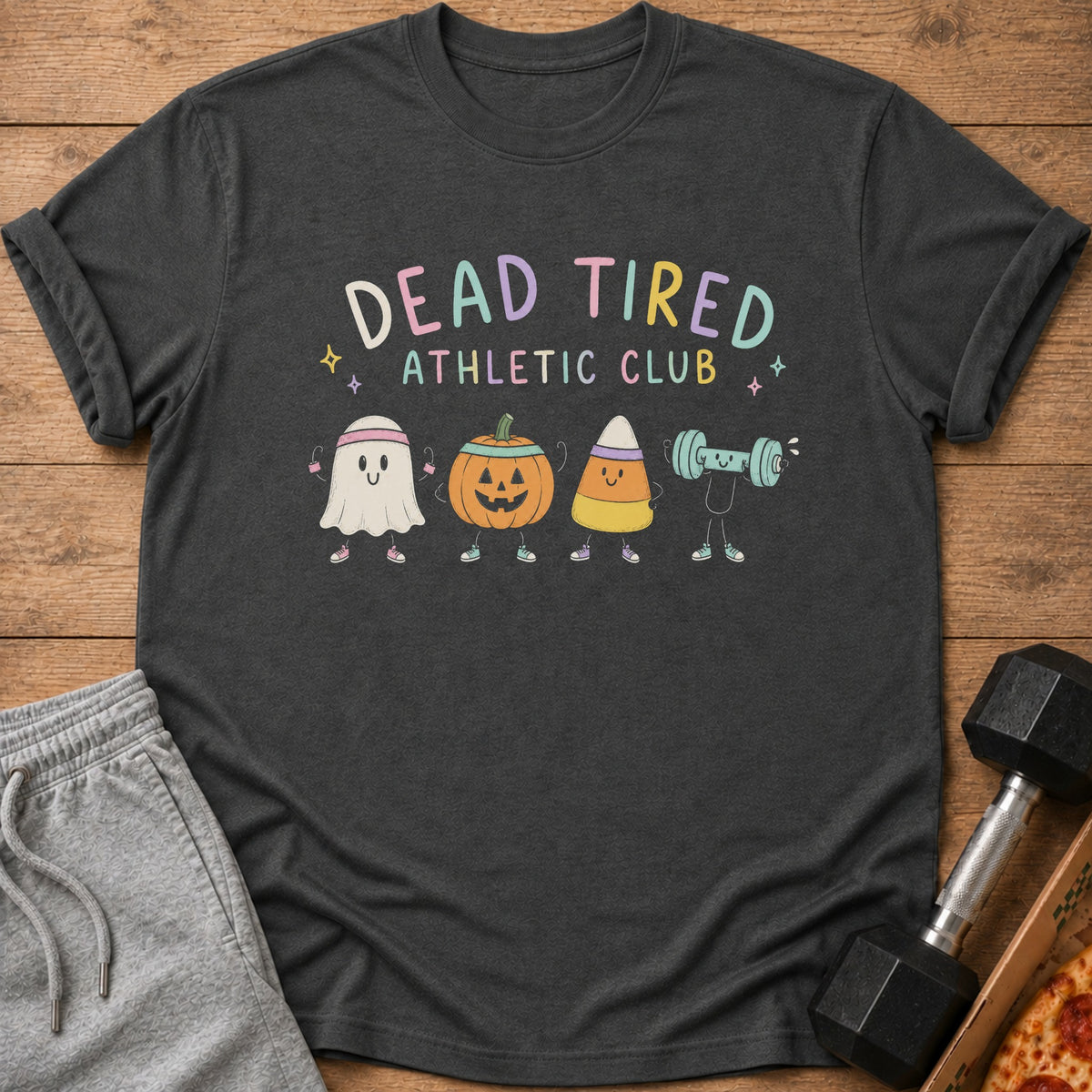 A dark gray t-shirt with the text Dead Tired Athletic Club and cartoon Halloween characters exercising.