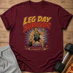 Maroon t-shirt with "LEG DAY SURVIVOR" text and illustration of a man lifting a kettlebell.
