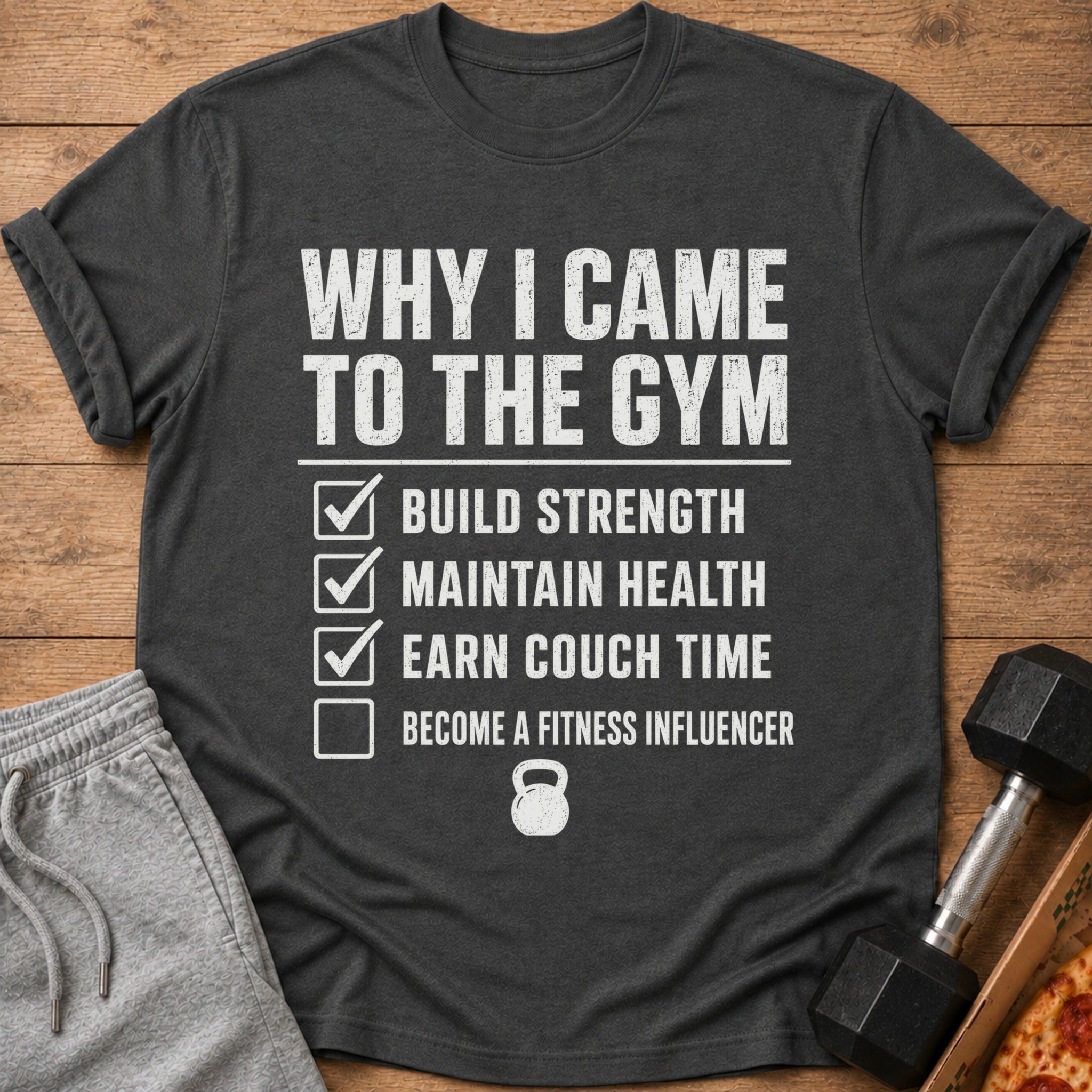 Dark gray t-shirt with "Why I Came to the Gym" list including build strength, maintain health, earn couch time.