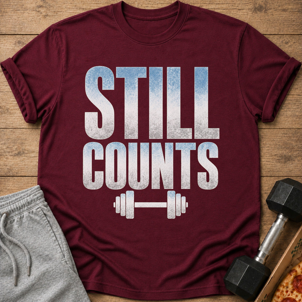 Maroon t-shirt with white and blue text "STILL COUNTS" and barbell graphic.