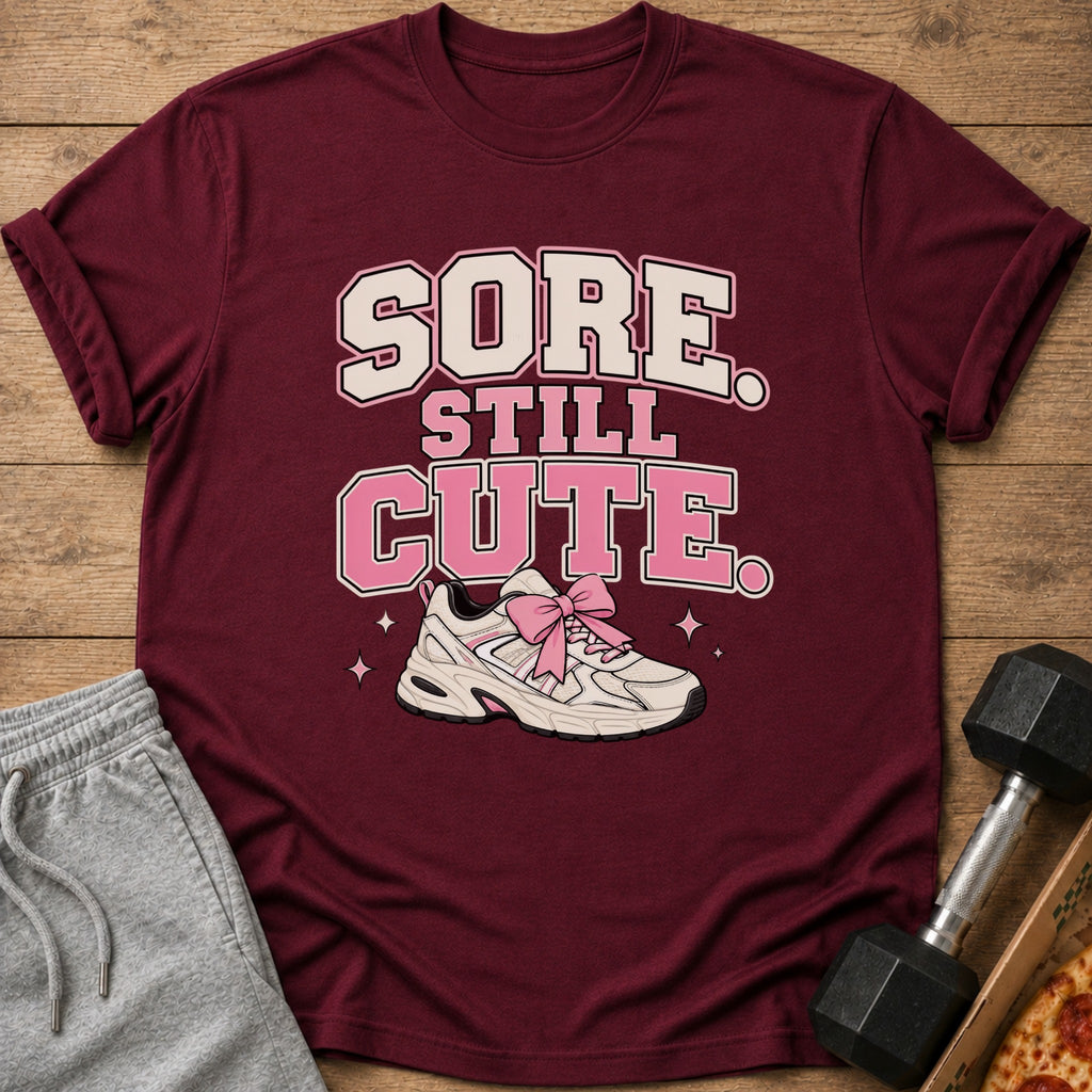 Maroon t-shirt with "SORE STILL CUTE" text and a sneaker with a pink bow.
