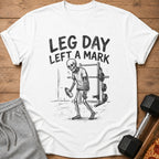 White t-shirt with skeleton design and text "LEG DAY LEFT A MARK".
