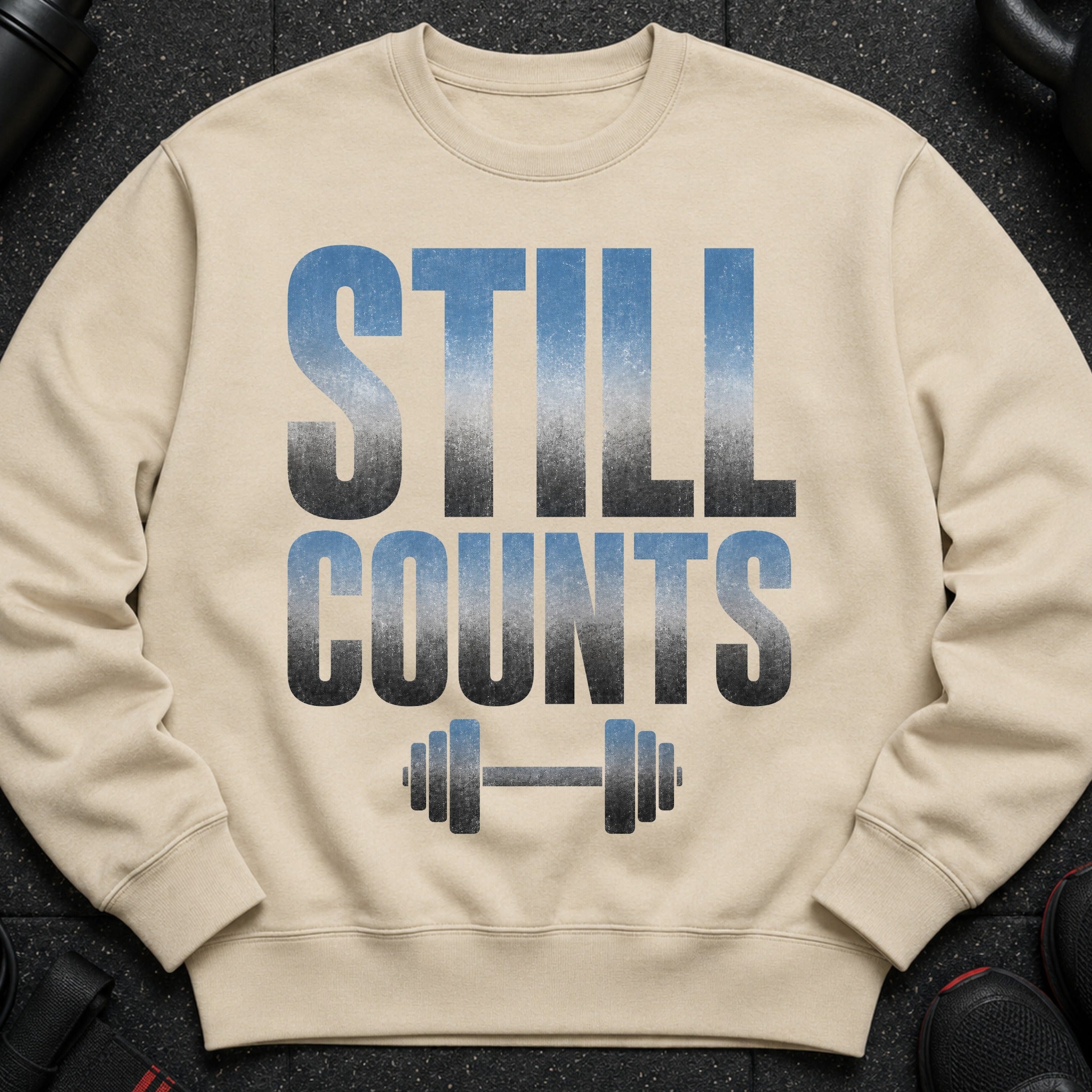 Light beige sweatshirt with "STILL COUNTS" text and dumbbell graphic.