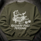 Olive green sweatshirt with a graphic of a possum on a foam roller and dumbbells. Text reads: "RECOVERY FEELS PERSONAL".