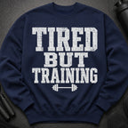 Navy sweatshirt with distressed white text "TIRED BUT TRAINING" and barbell graphic.