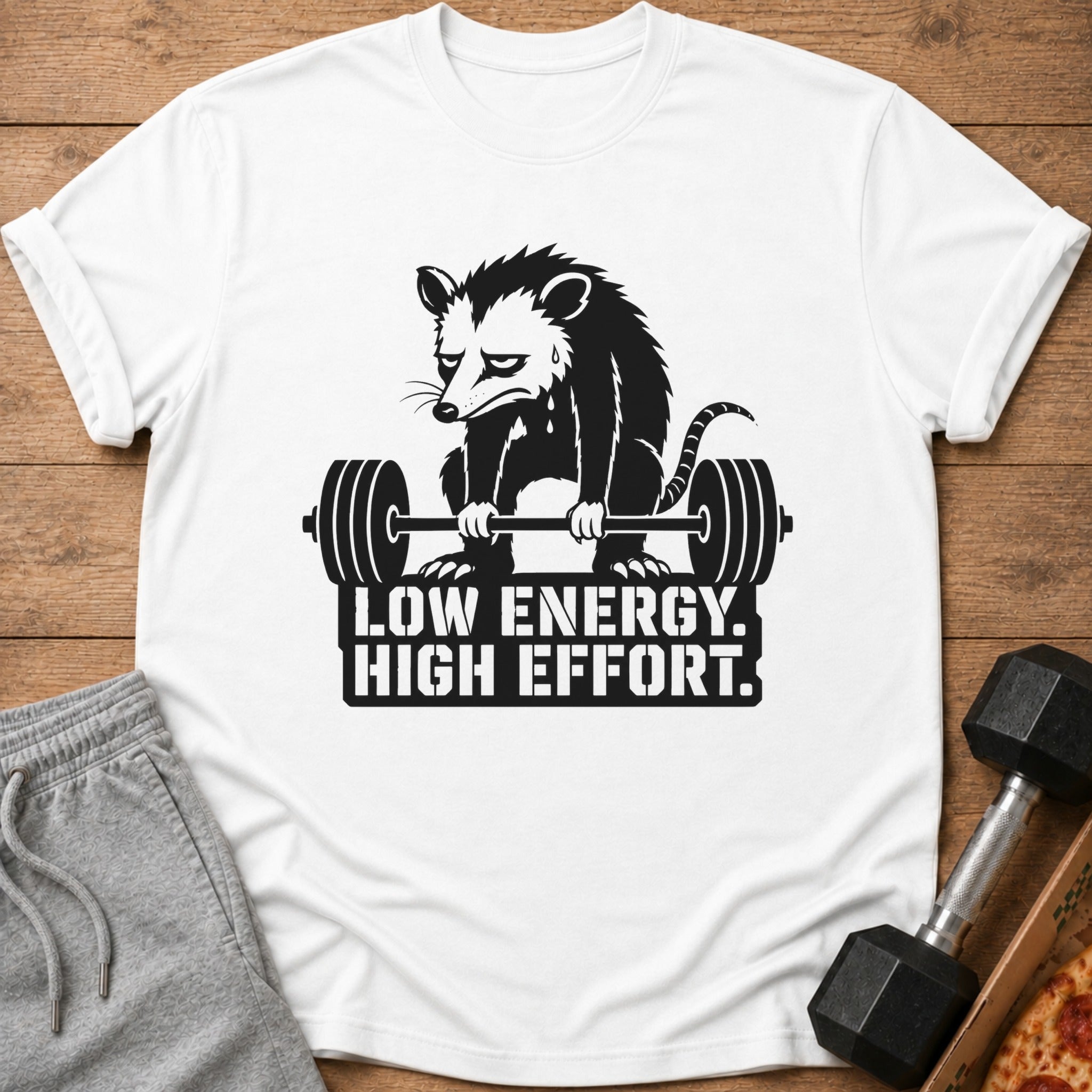 White t-shirt with a tired opossum lifting a barbell and the text "LOW ENERGY. HIGH EFFORT."