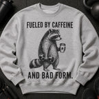 Gray sweatshirt with graphic of raccoon holding dumbbell and coffee cup, text: Fueled by caffeine and bad form.