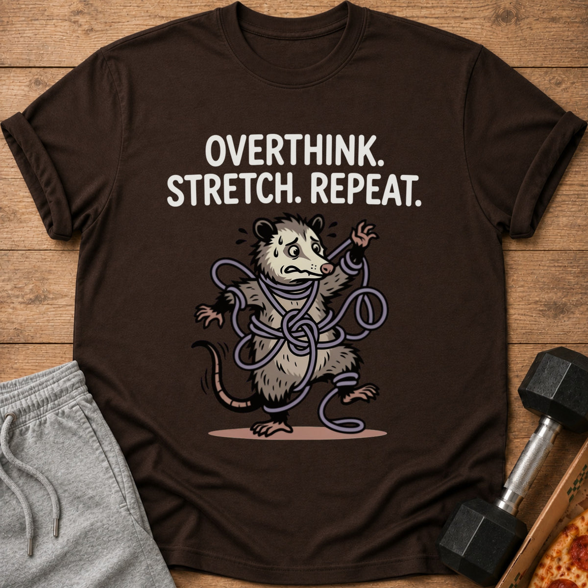 Brown t-shirt with a possum tangled in ropes and text "OVERTHINK. STRETCH. REPEAT."