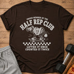 Brown t-shirt with "Proud Member of the Half Rep Club" text and cartoon weight on skateboard.