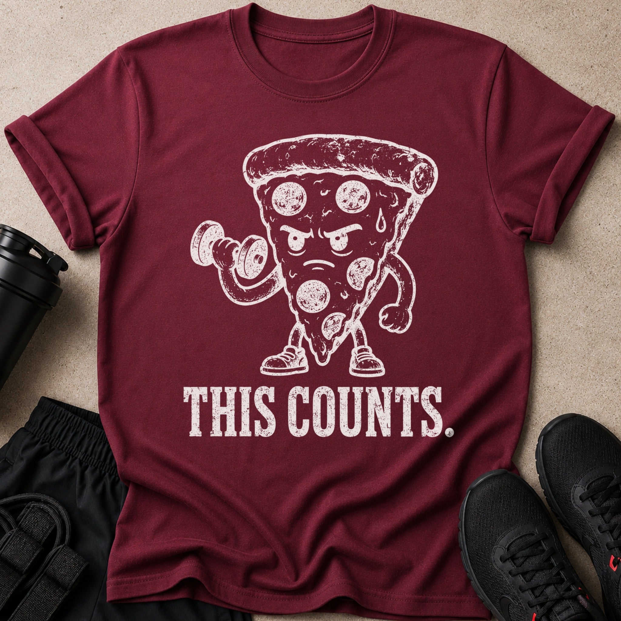 Maroon t-shirt with white graphic of pizza slice lifting dumbbell and text "THIS COUNTS."