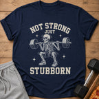 Navy t-shirt with skeleton squatting barbell, text "NOT STRONG JUST STUBBORN".
