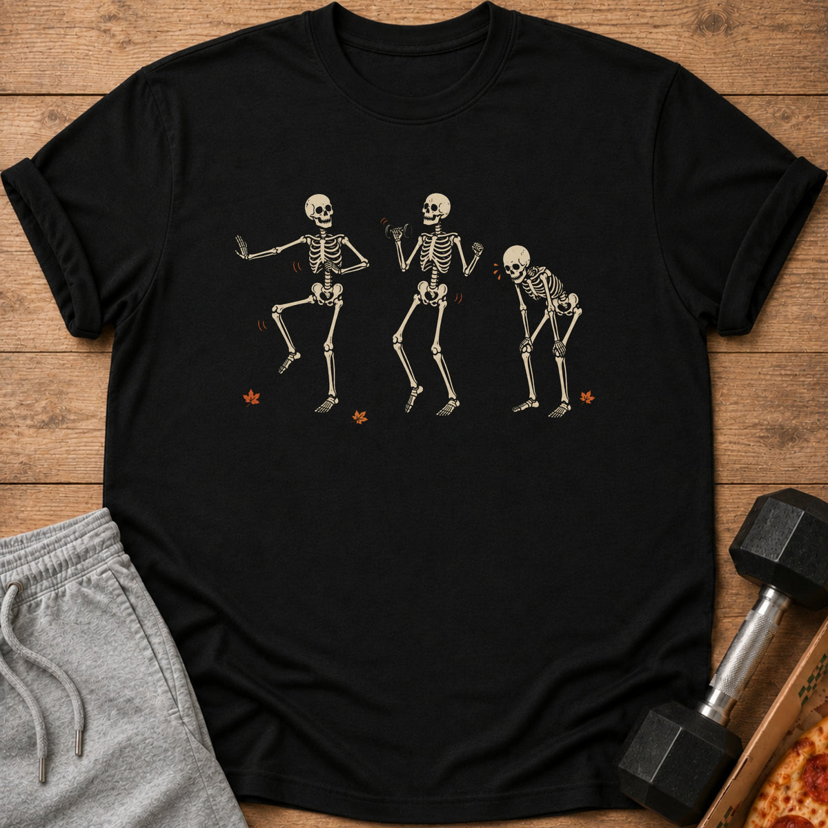 Black t-shirt with three dancing skeletons and falling leaves graphic.