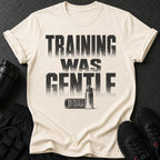 Cream t-shirt with distressed black text "TRAINING WAS GENTLE" and fitness accessories.