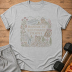 Light grey t-shirt with a line drawing of mountains, trees, and a hiker.