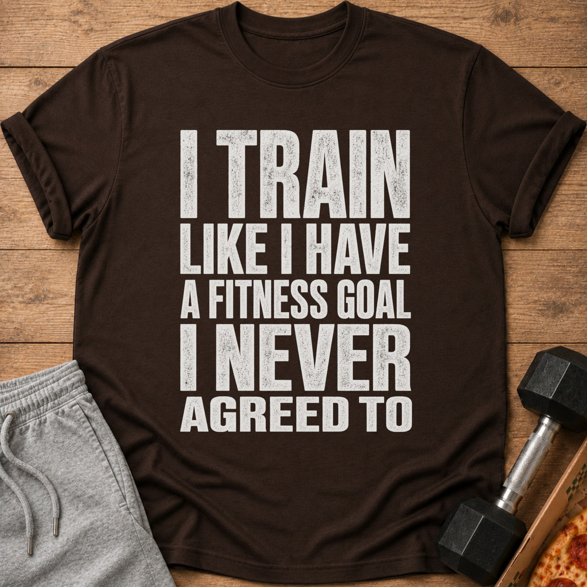 Brown t-shirt with white text: "I TRAIN LIKE I HAVE A FITNESS GOAL I NEVER AGREED TO."