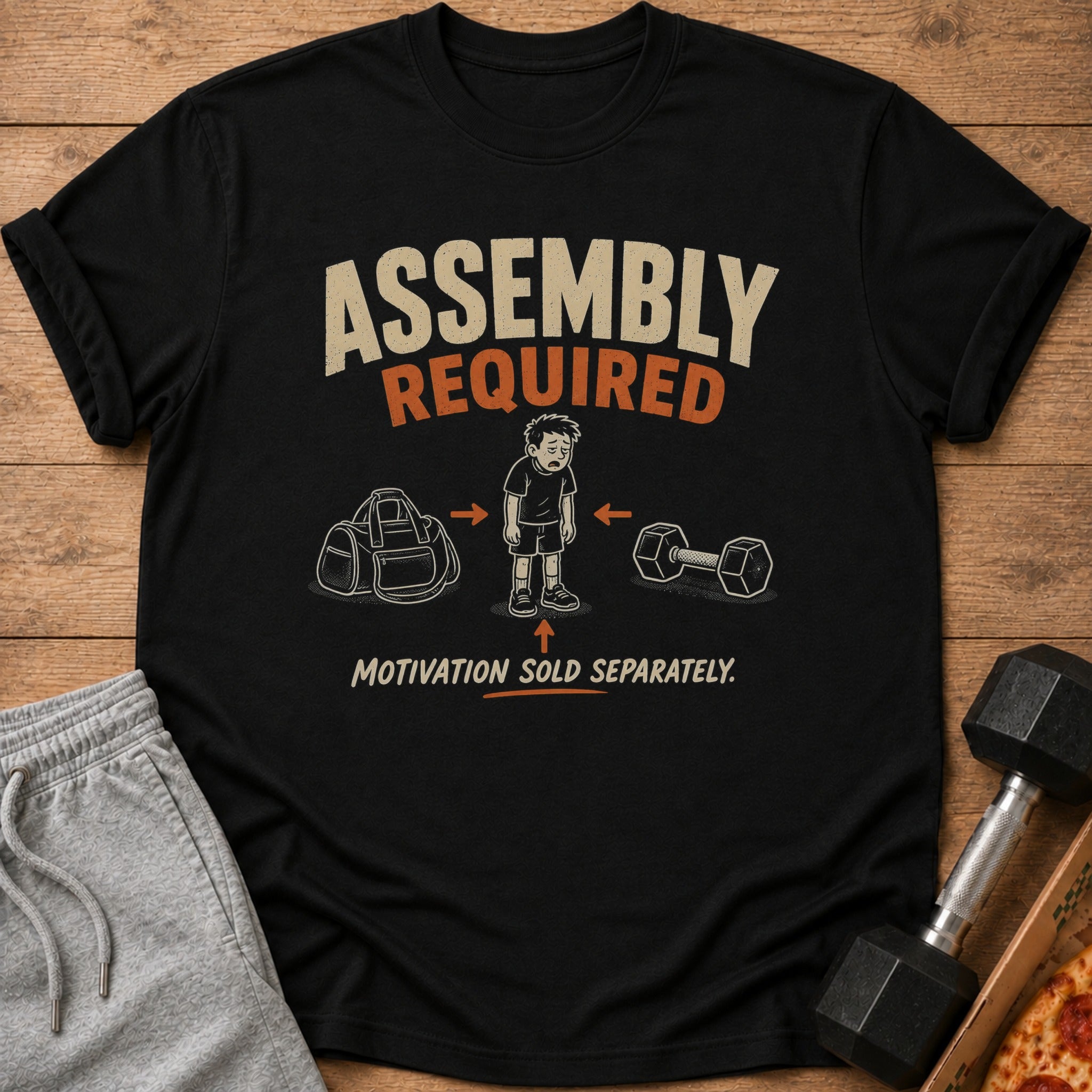 Black t-shirt with "Assembly Required" text and a cartoon of a tired person between a gym bag and dumbbell.