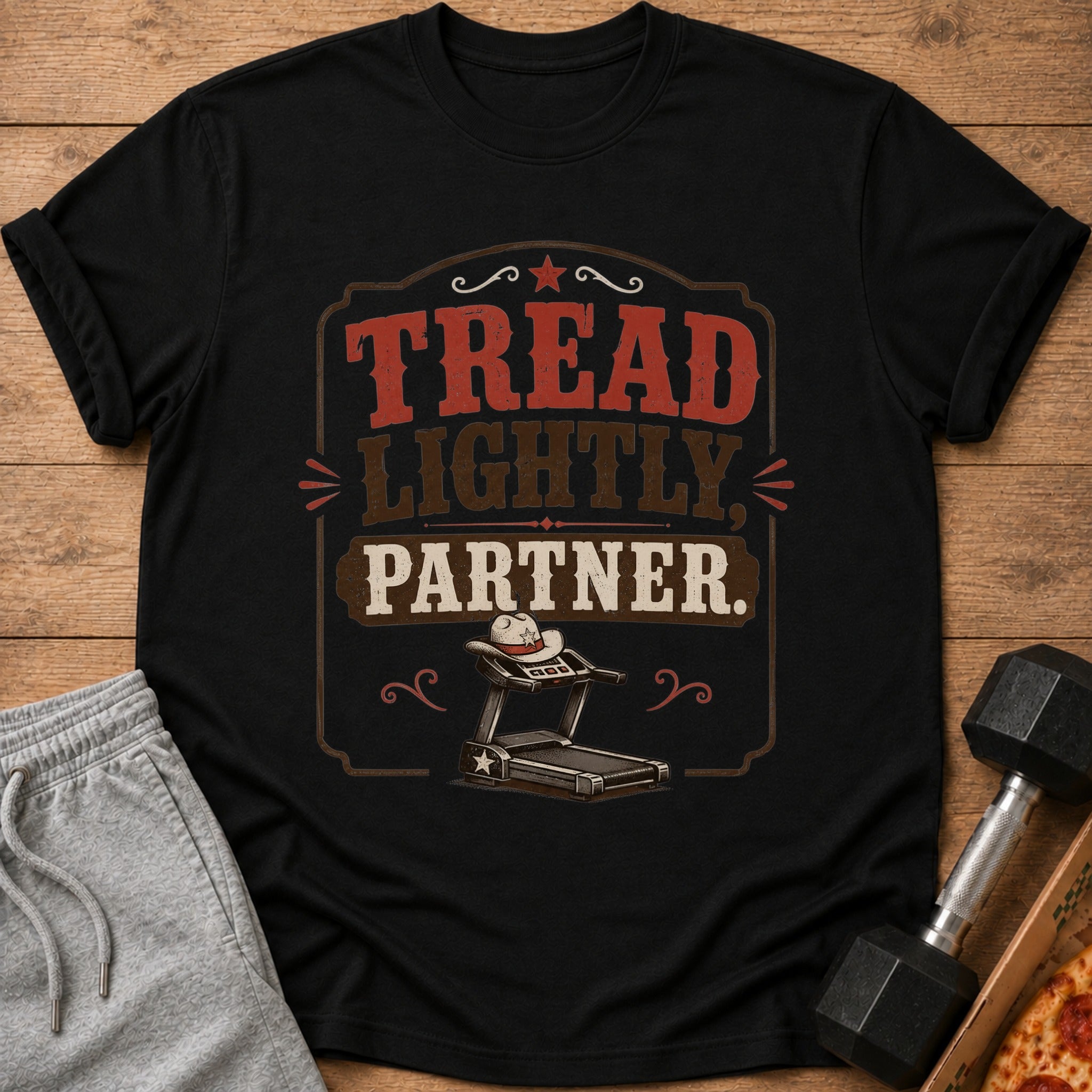 Black t-shirt with "TREAD LIGHTLY, PARTNER." text above a cowboy hat on a treadmill.