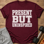 Maroon t-shirt with distressed white text reading "PRESENT BUT UNINSPIRED".