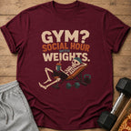 Maroon t-shirt with skeleton on weight bench and text "GYM? SOCIAL HOUR WITH WEIGHTS."