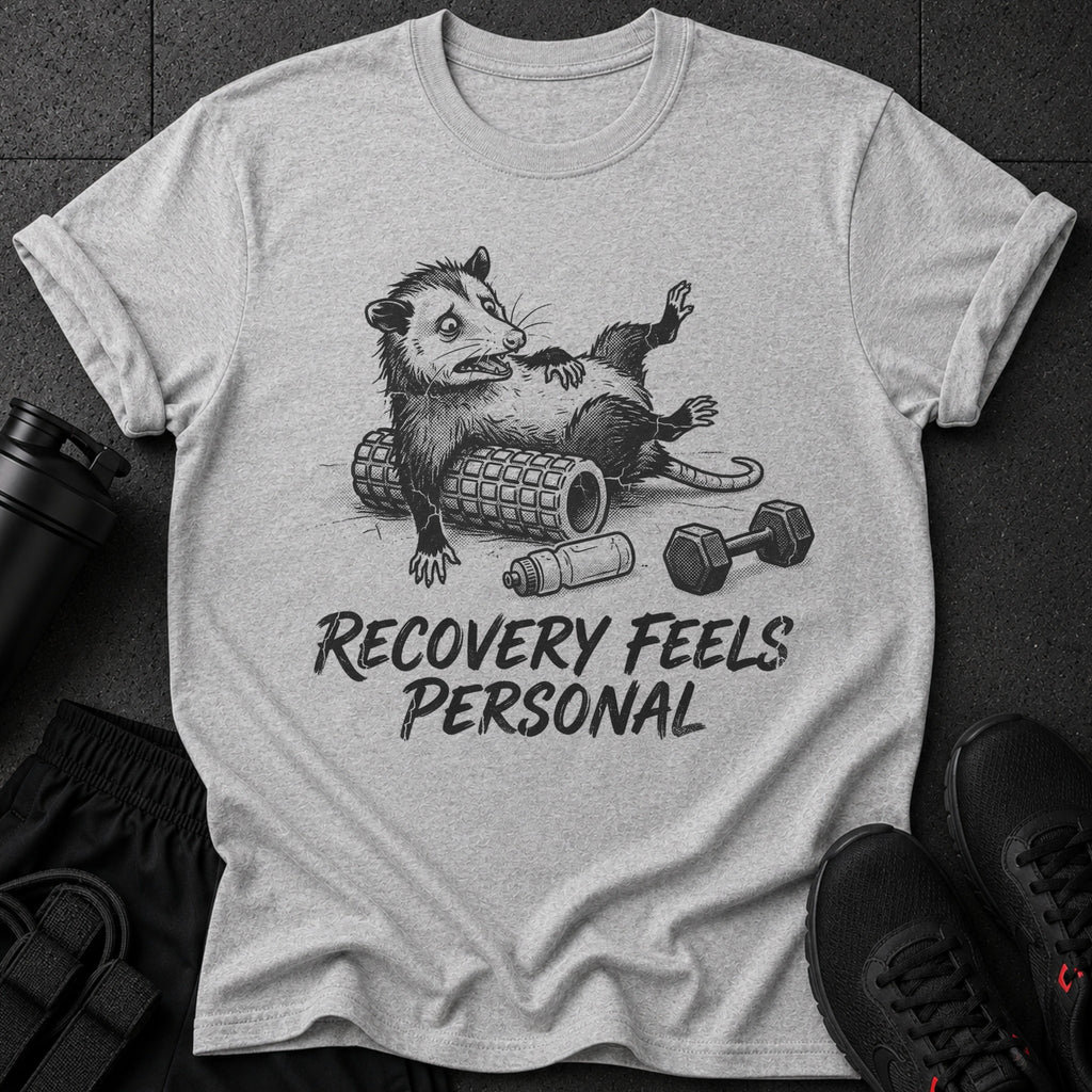 T-shirt with opossum on foam roller and dumbbell, text reads "Recovery Feels Personal".