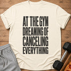 Cream t-shirt with black text "At the Gym Dreaming of Canceling Everything."