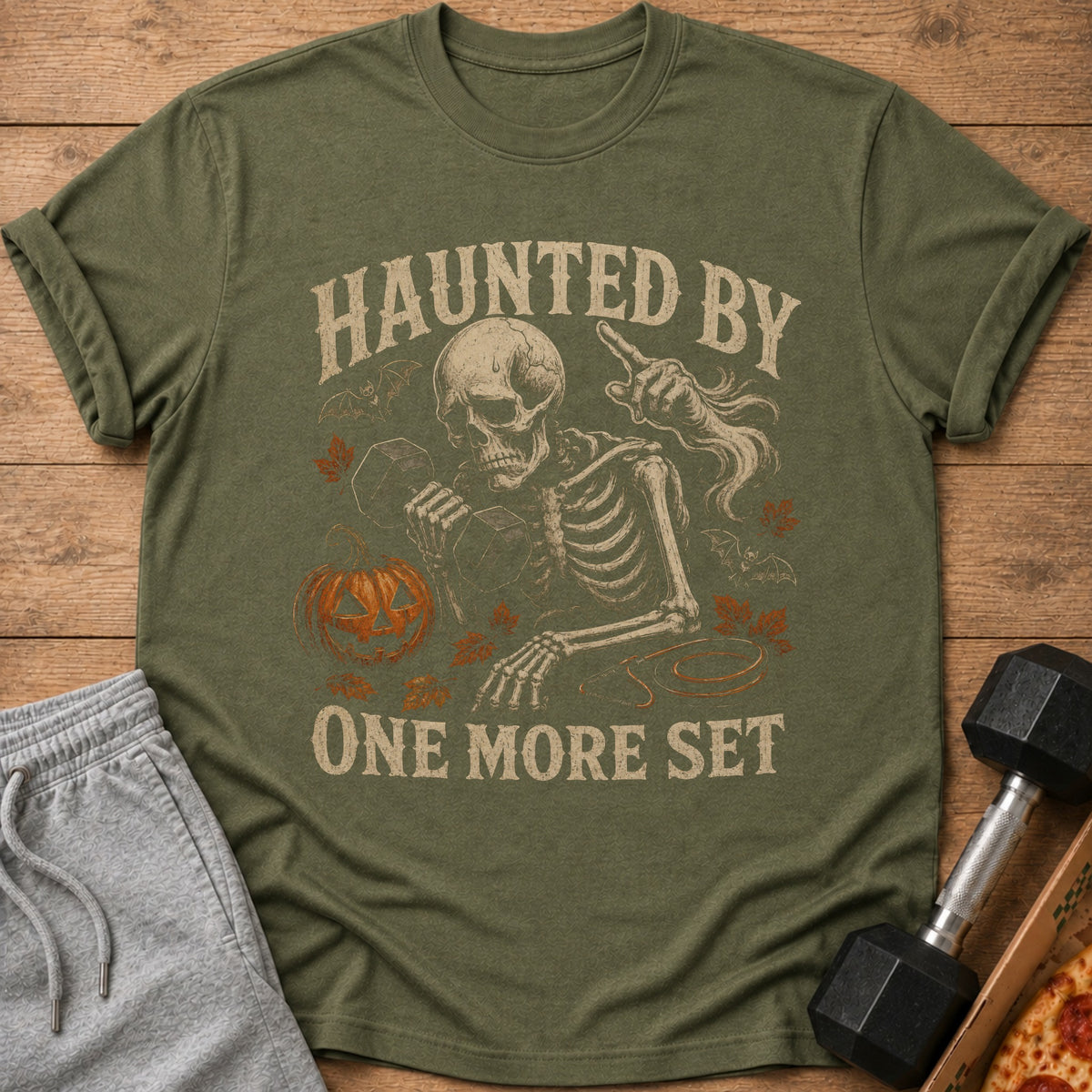 Green t-shirt with skeleton lifting weights and text "Haunted by One More Set".