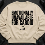 Light beige crewneck sweatshirt with black text reading "EMOTIONALLY UNAVAILABLE FOR CARDIO" and a treadmill graphic.