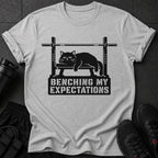Light grey t-shirt with black graphic of cat on weight bench and text.