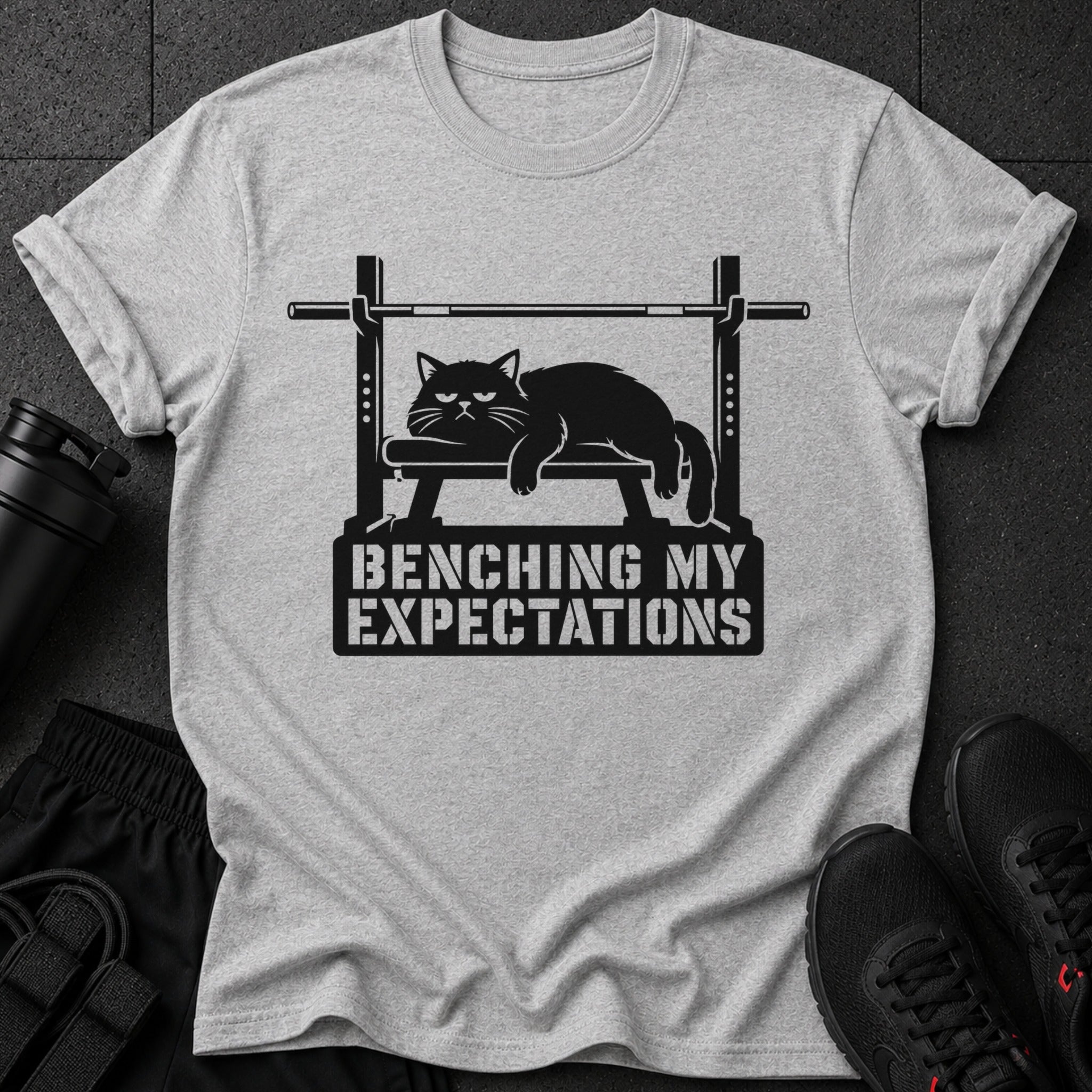 Light grey t-shirt with black graphic of cat on weight bench and text.