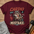 Maroon t-shirt with a raccoon on an elliptical saying "Cardio Was A Mistake".