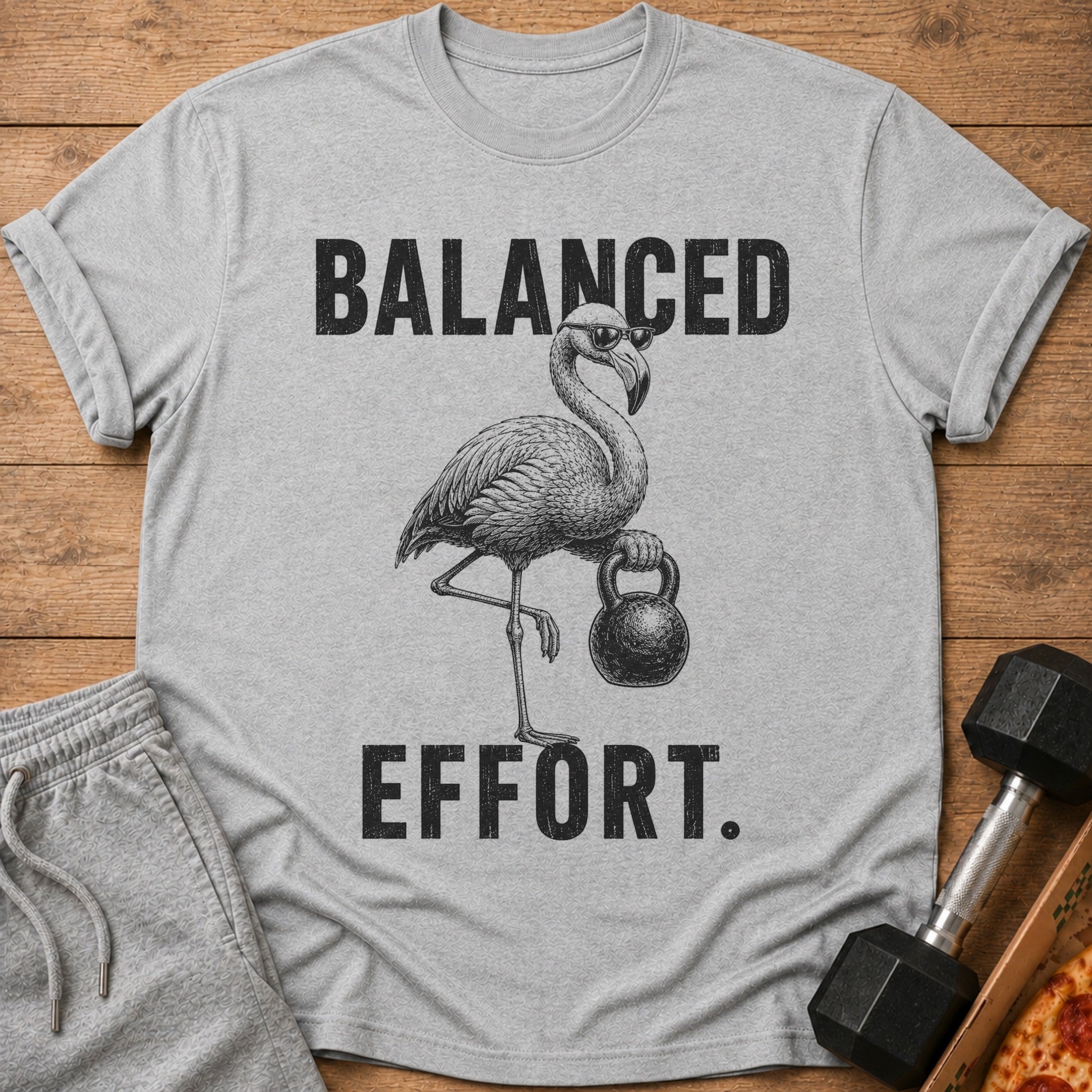 T-shirt with drawing of flamingo in sunglasses holding dumbbell, text says "BALANCED EFFORT."