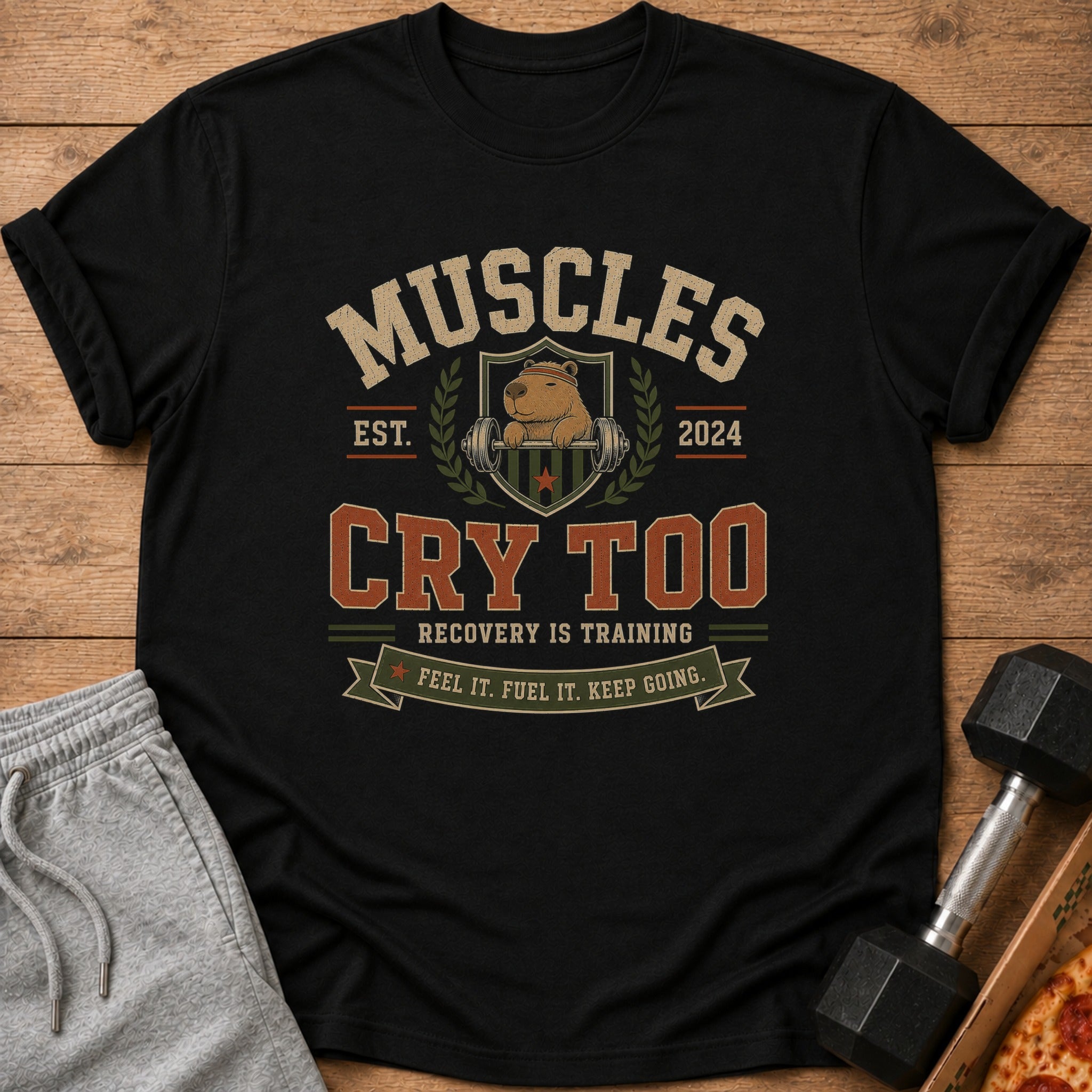 Black t-shirt with "Muscles Cry Too" text and a capybara lifting weights.