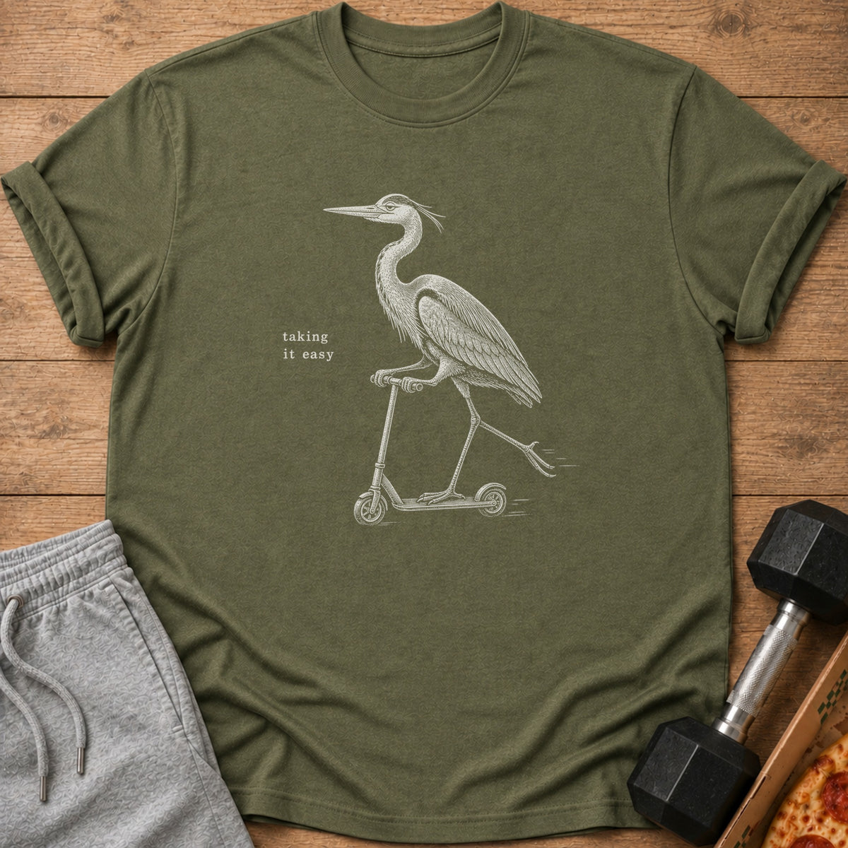 Green t-shirt with white illustration of a heron riding a scooter and text.