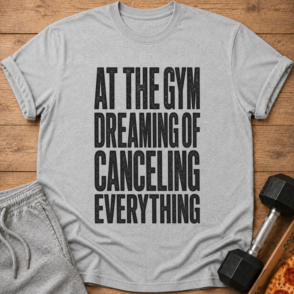 Grey t-shirt with black text reading "AT THE GYM DREAMING OF CANCELING EVERYTHING".