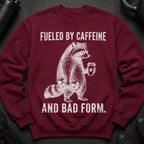 Maroon sweatshirt with a graphic of a raccoon, dumbbells, and coffee cup with text.