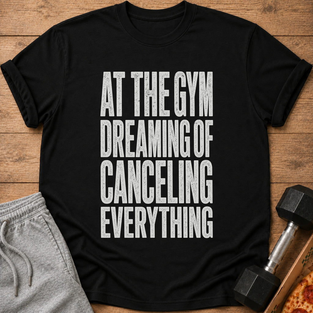 Black t-shirt with white text reading "AT THE GYM DREAMING OF CANCELING EVERYTHING".