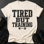 T-shirt with text "TIRED BUT TRAINING" and barbell graphic.