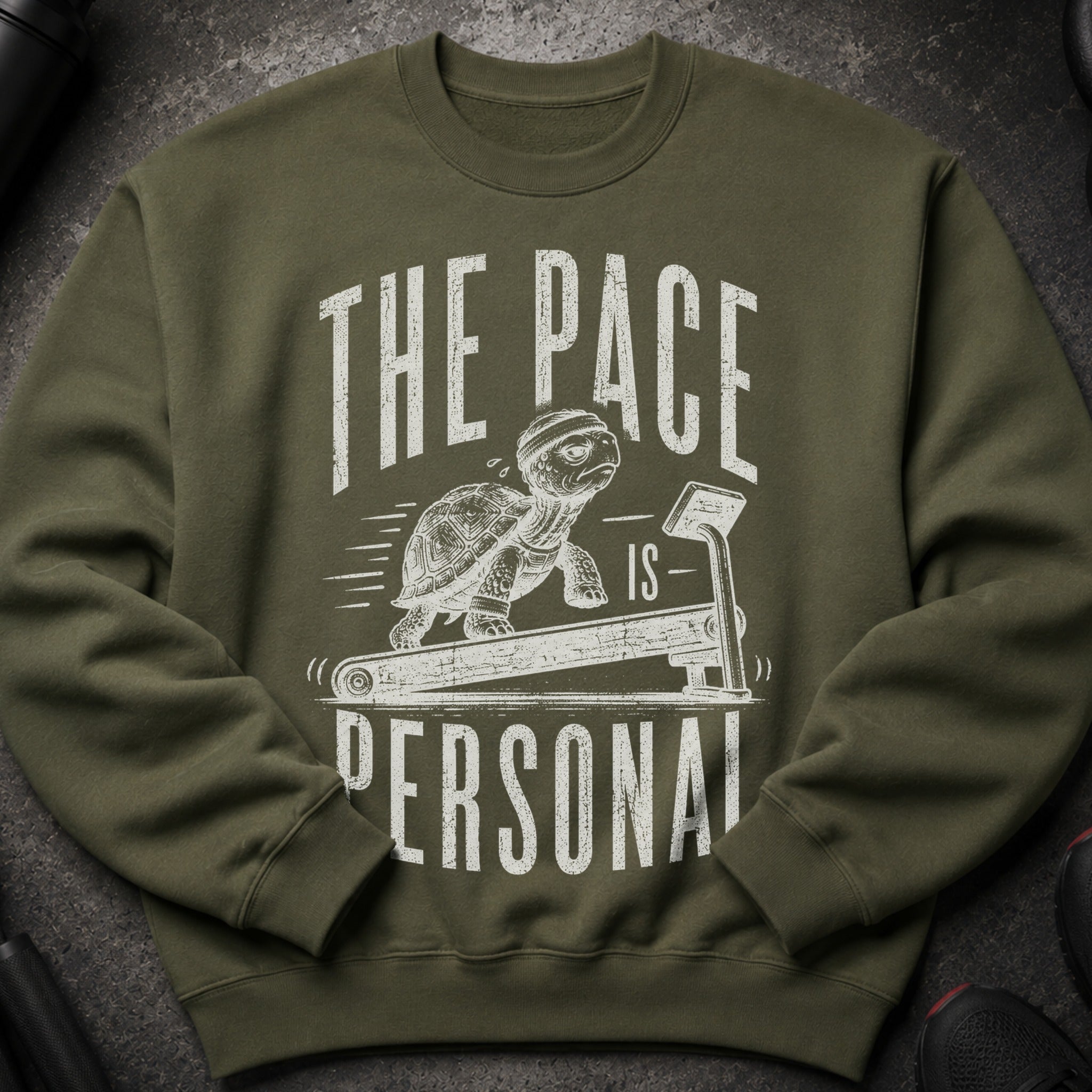 Green sweatshirt with a graphic of a tortoise on a treadmill, reading "The Pace is Personal".