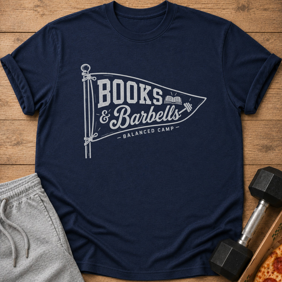 Navy t-shirt with "Books & Barbells - Balanced Camp" text design on a pennant.