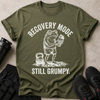 Olive green t-shirt with a distressed graphic of a grumpy frog holding a shaker bottle and the text "Recovery Mode Still Grumpy."