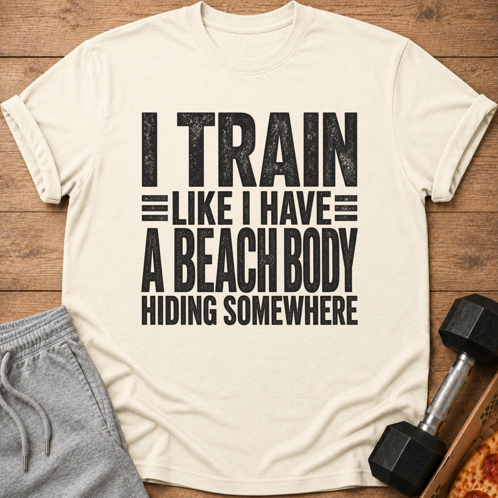 Cream t-shirt with black text reading "I TRAIN LIKE I HAVE A BEACH BODY HIDING SOMEWHERE".