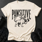 Cream t-shirt with distressed text "PAWSITIVE" above a happy dog lifting a dumbbell.