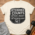 T-shirt with "Attendance Counts: Body: Present, Motivation: Absent" text, kettlebell, and shaker bottle.