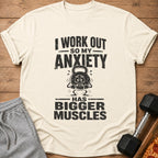 Cream t-shirt with text "I work out so my anxiety has bigger muscles" and a distressed kettlebell graphic.